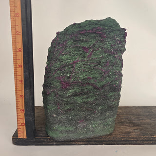 ruby in zoisite rough gemstone specimen on wooden shelf with ruler for scale