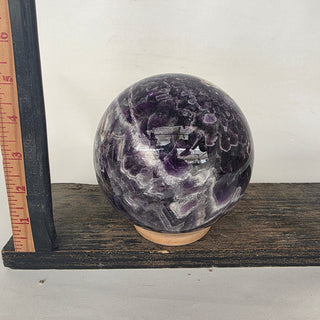 dreamy amethyst sphere on wooden stand with ruler for scale; stand not included
